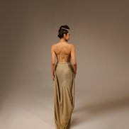Woman wearing a long, elegant dress with a high slit on a plain background