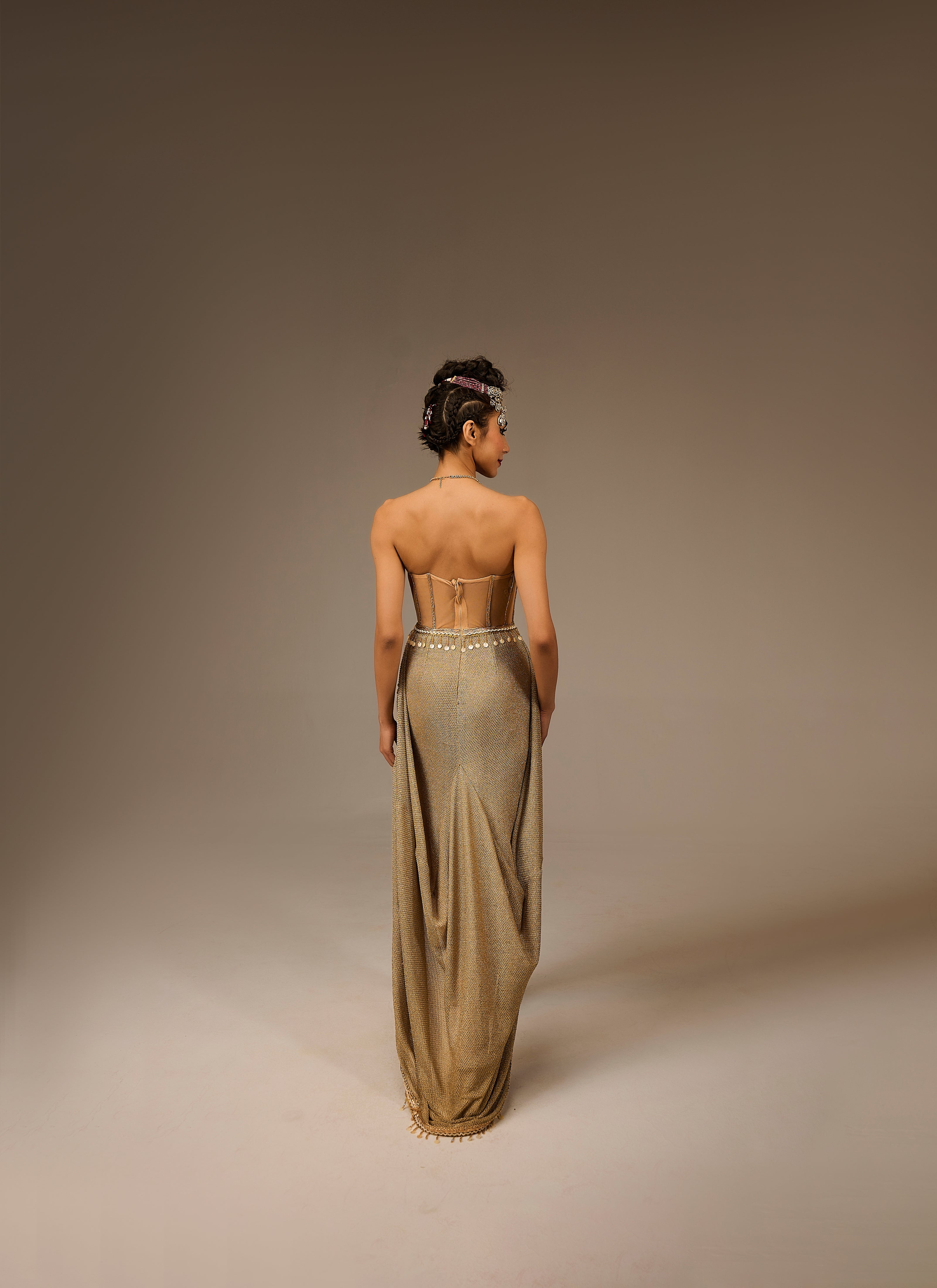 Woman wearing a long, elegant dress with a high slit on a plain background