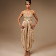 Woman wearing a beige and gold dress with a headpiece against a brown background