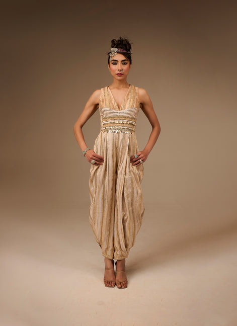 Woman wearing a beige and gold dress with a headpiece against a brown background