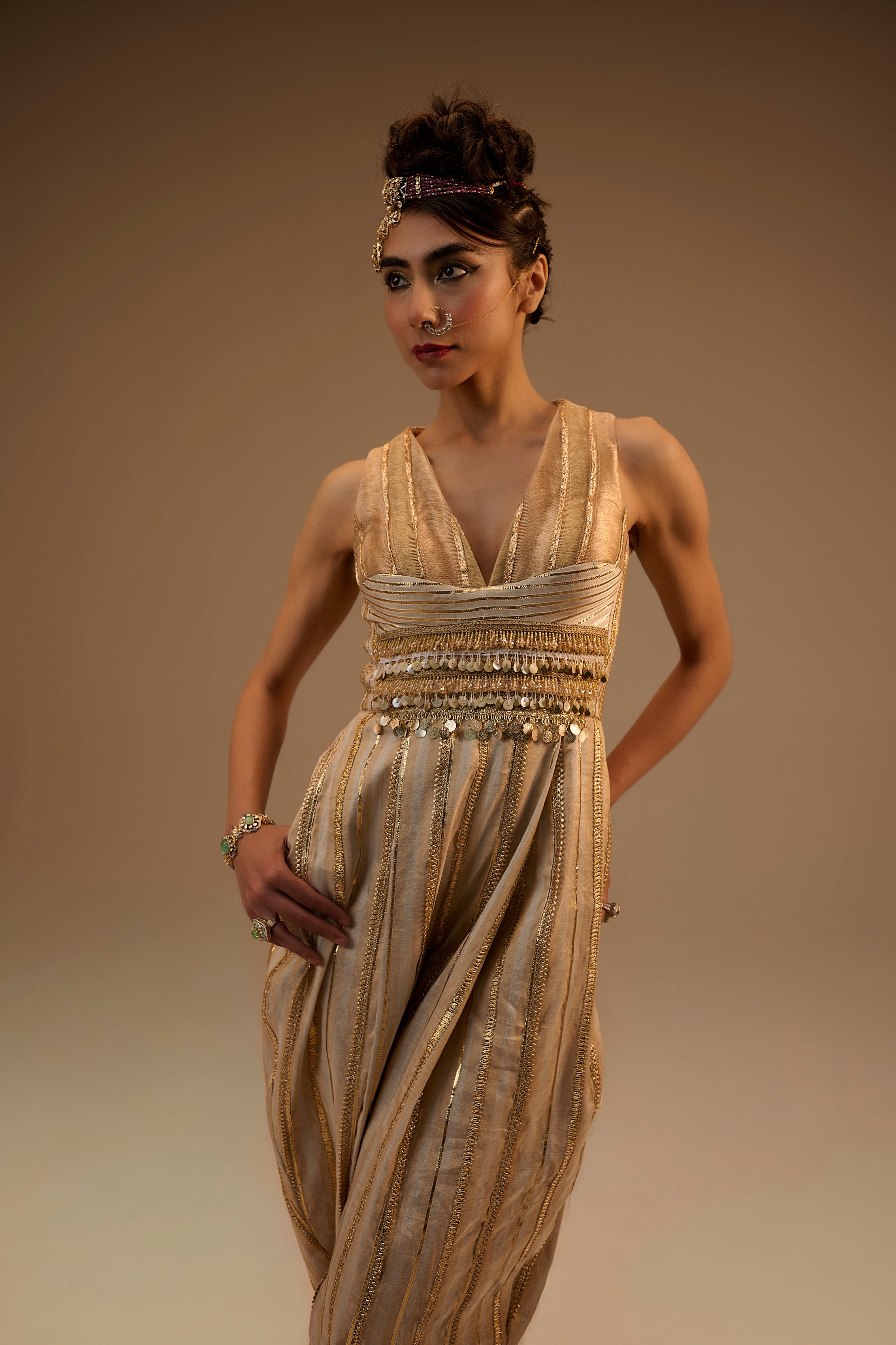 Woman wearing a gold evening gown against a beige background