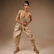 Woman wearing a gold and white patterned outfit against a brown background