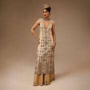 Woman wearing a long, ornate dress with intricate patterns on a beige background