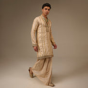 Man wearing a traditional beige kurta with pants on a plain background