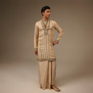 Person wearing a traditional outfit with intricate patterns on a plain background