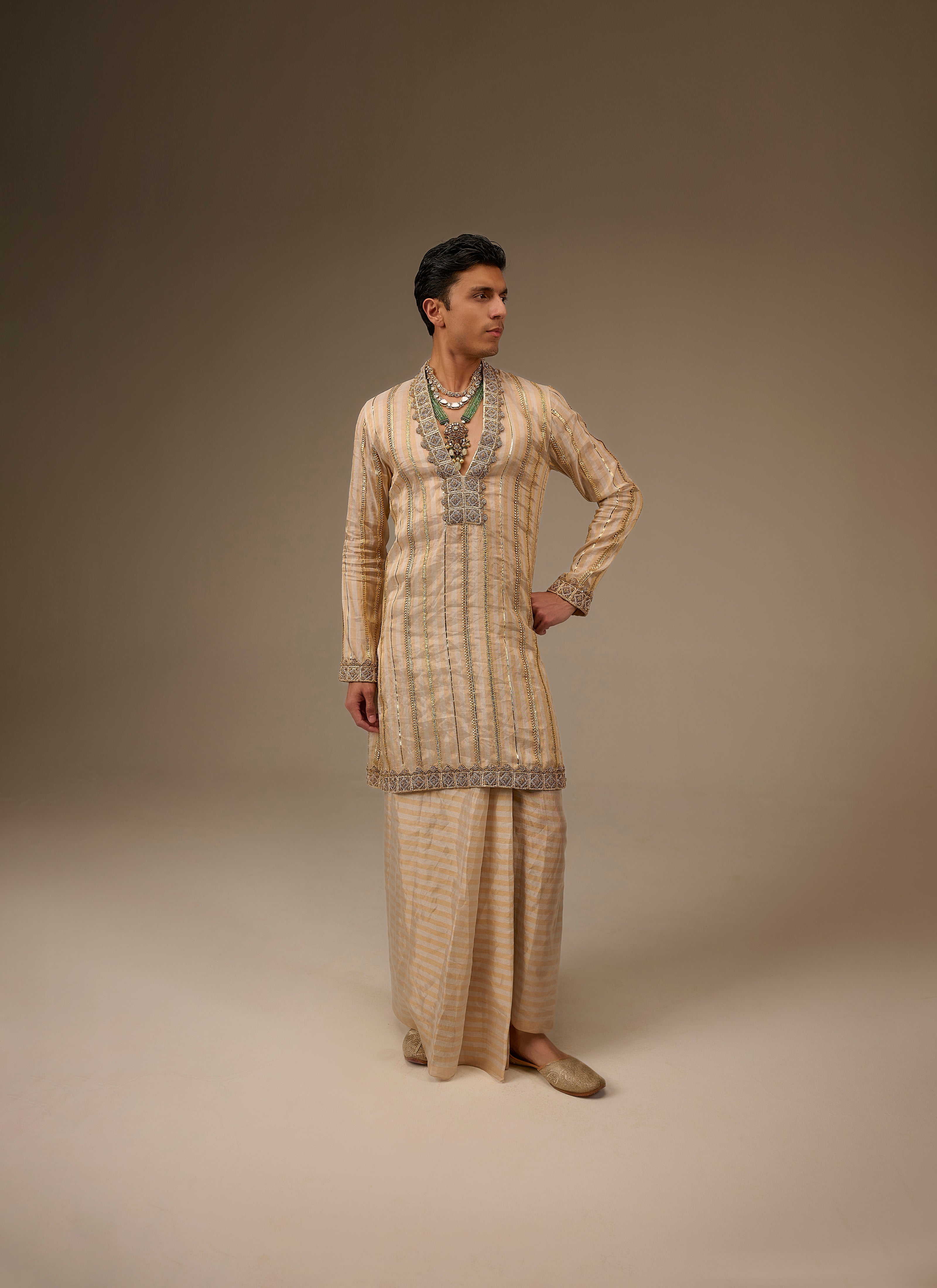 Person wearing a traditional outfit with intricate patterns on a plain background