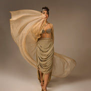 Woman in a flowing beige dress against a plain background