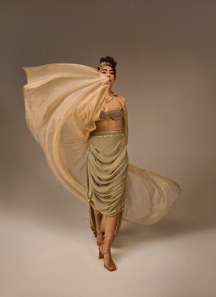 Woman in a flowing beige dress against a plain background