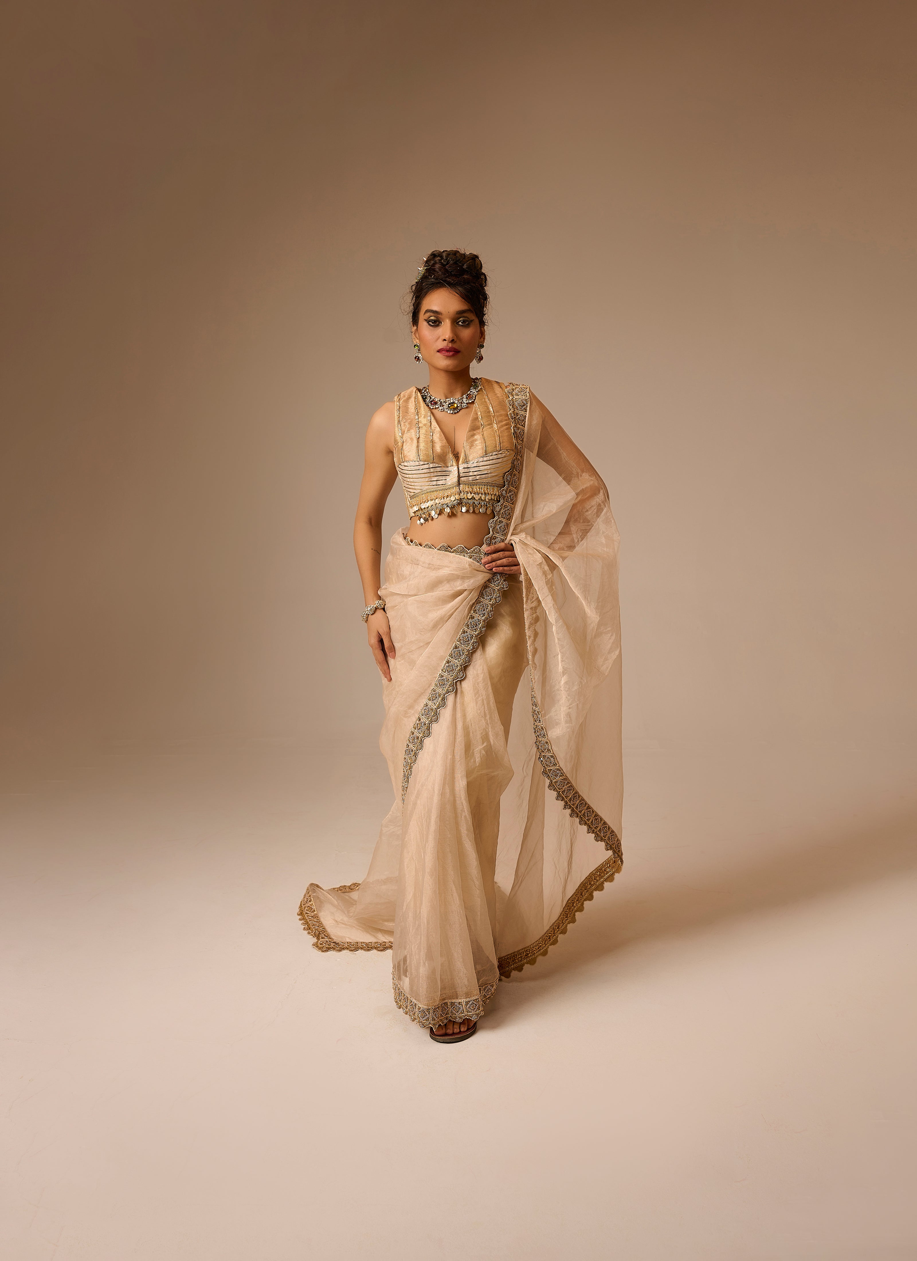 Woman wearing a beige saree with intricate designs on a beige background
