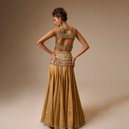 Woman wearing a gold dress with intricate detailing on a beige background