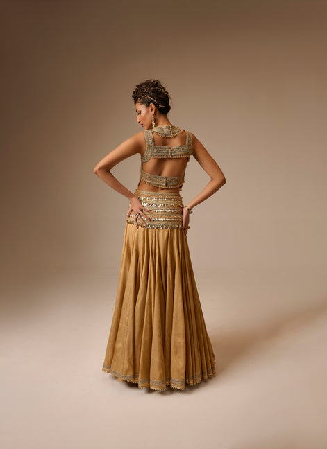 Woman wearing a gold dress with intricate detailing on a beige background