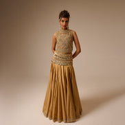 Woman wearing a gold embroidered gown against a beige background