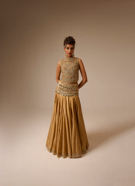 Woman wearing a gold embroidered gown against a beige background