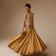 Woman wearing a gold traditional outfit with intricate designs on a beige background