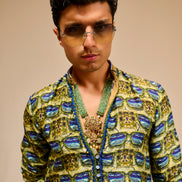 Man wearing a patterned jacket and sunglasses against a beige background