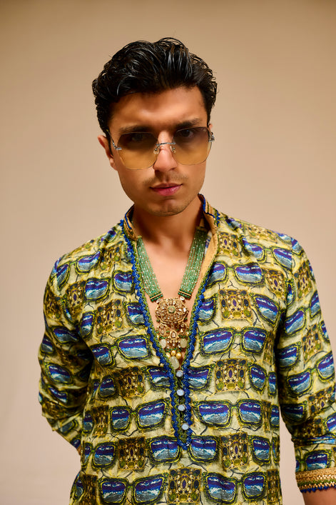 Man wearing a patterned jacket and sunglasses against a beige background