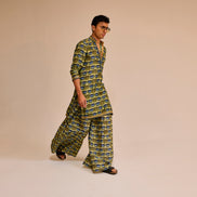 Man wearing a green and blue patterned outfit on a beige background