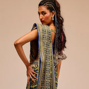 Woman wearing a long, intricately designed dress with a beige background