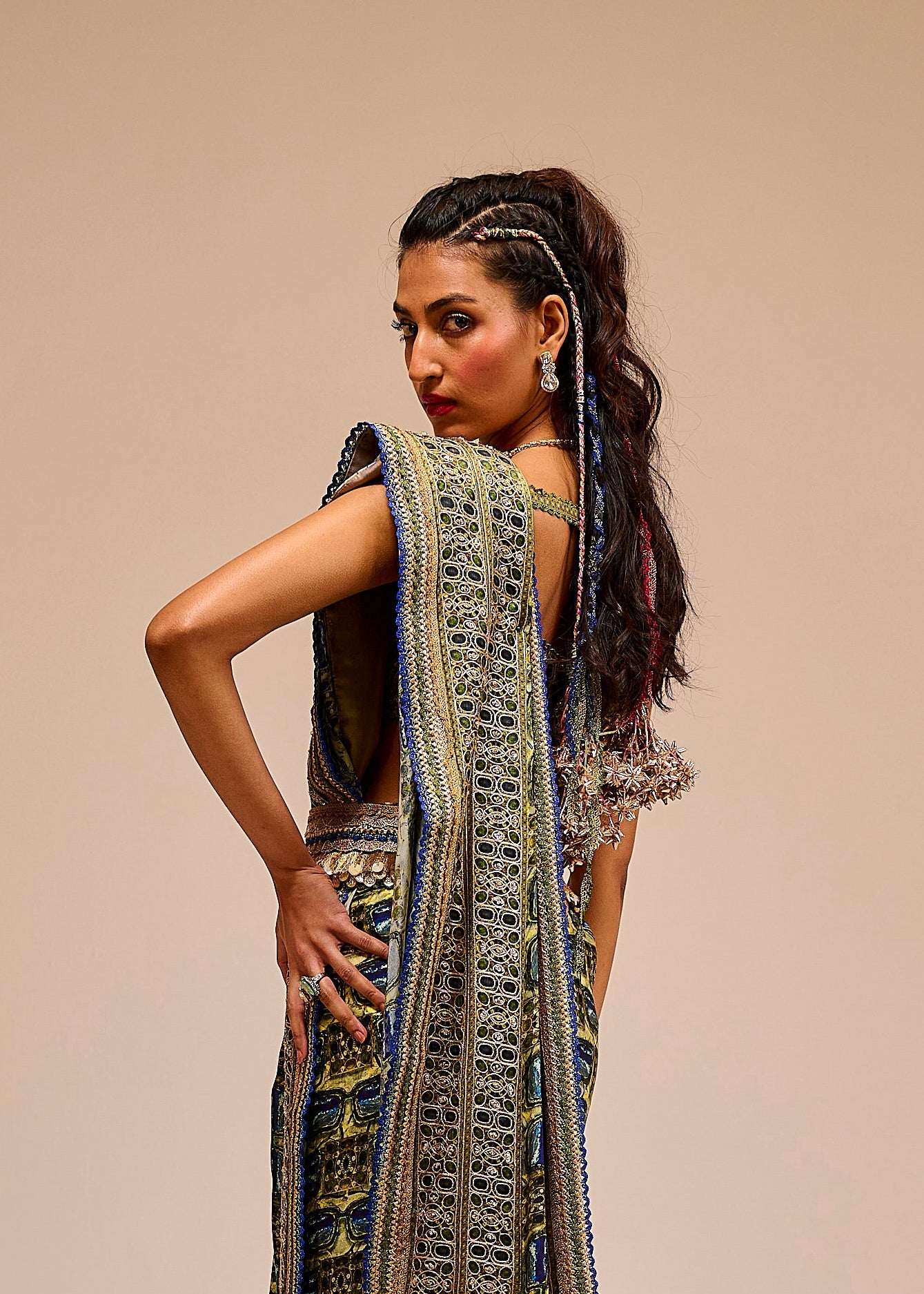 Woman wearing a long, intricately designed dress with a beige background