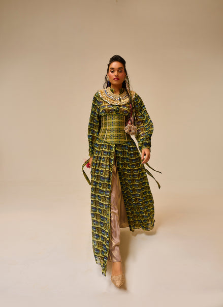 Woman wearing a long, patterned dress against a plain background