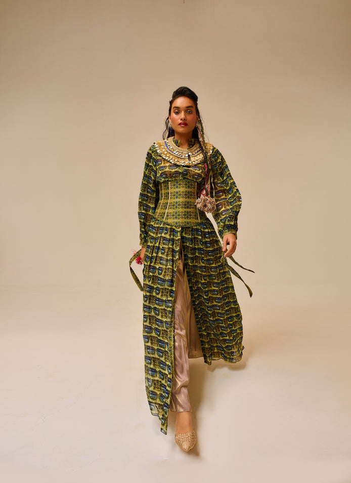 Woman wearing a long, patterned dress against a plain background