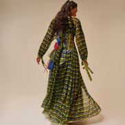 Woman wearing a long, patterned dress against a beige background