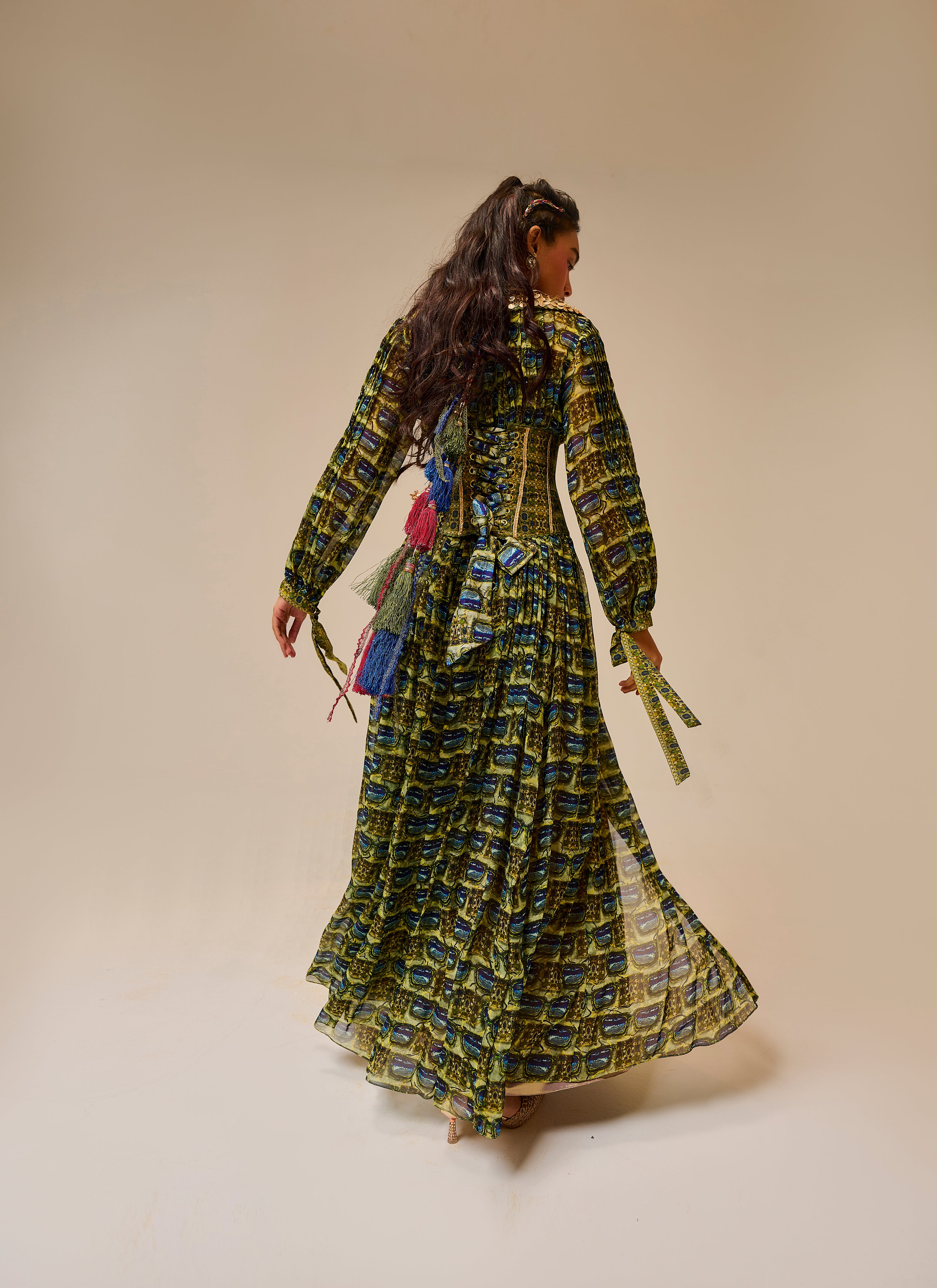 Woman wearing a long, patterned dress against a beige background