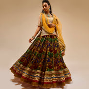 Woman wearing a traditional outfit with a yellow dupatta on a beige background