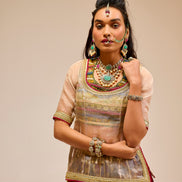 Woman in traditional attire with jewelry against a beige background