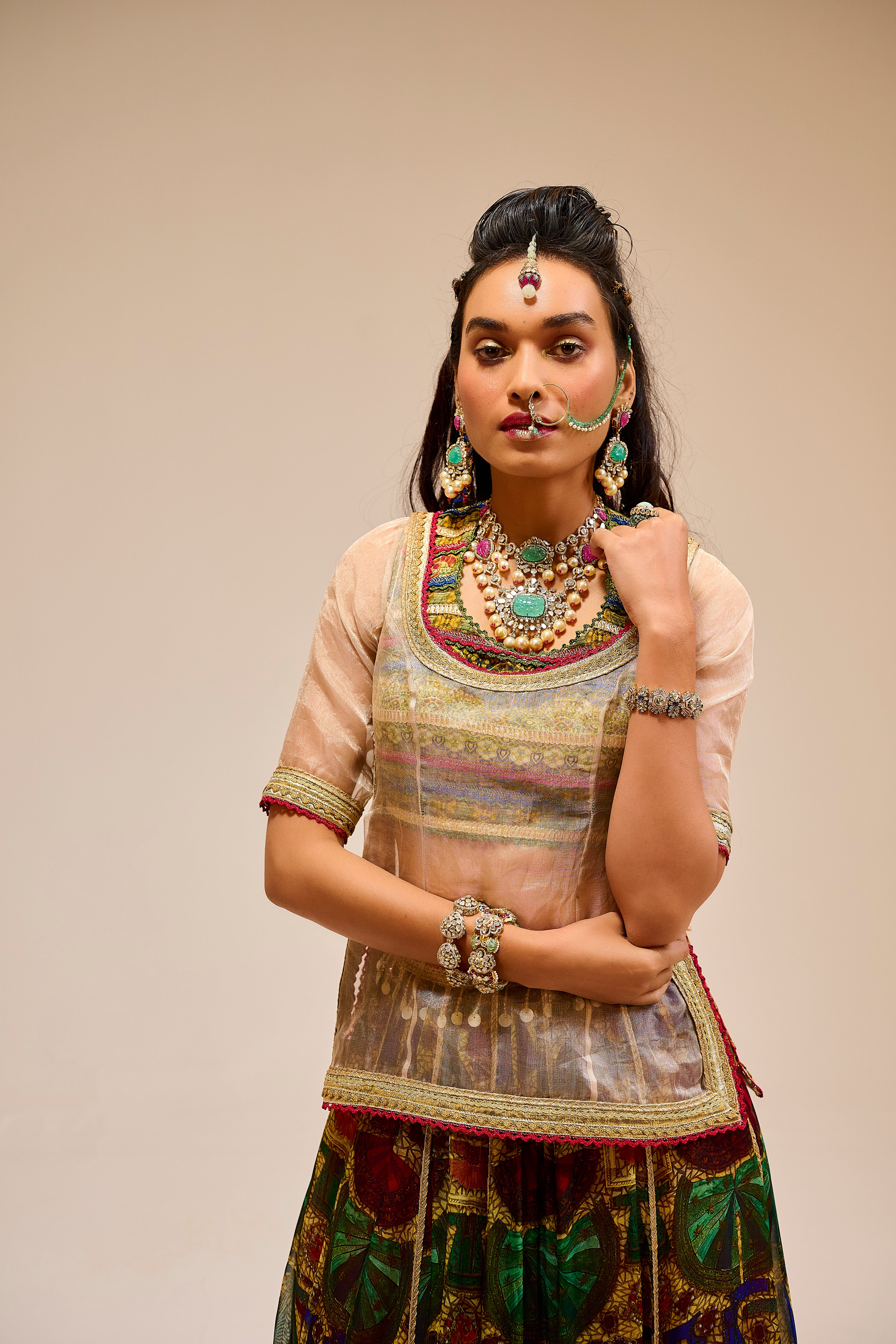 Woman in traditional attire with jewelry against a beige background
