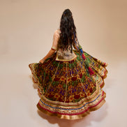 Woman in a colorful traditional outfit with a patterned skirt on a beige background