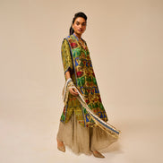 Woman wearing a colorful traditional outfit with a patterned shawl on a beige background