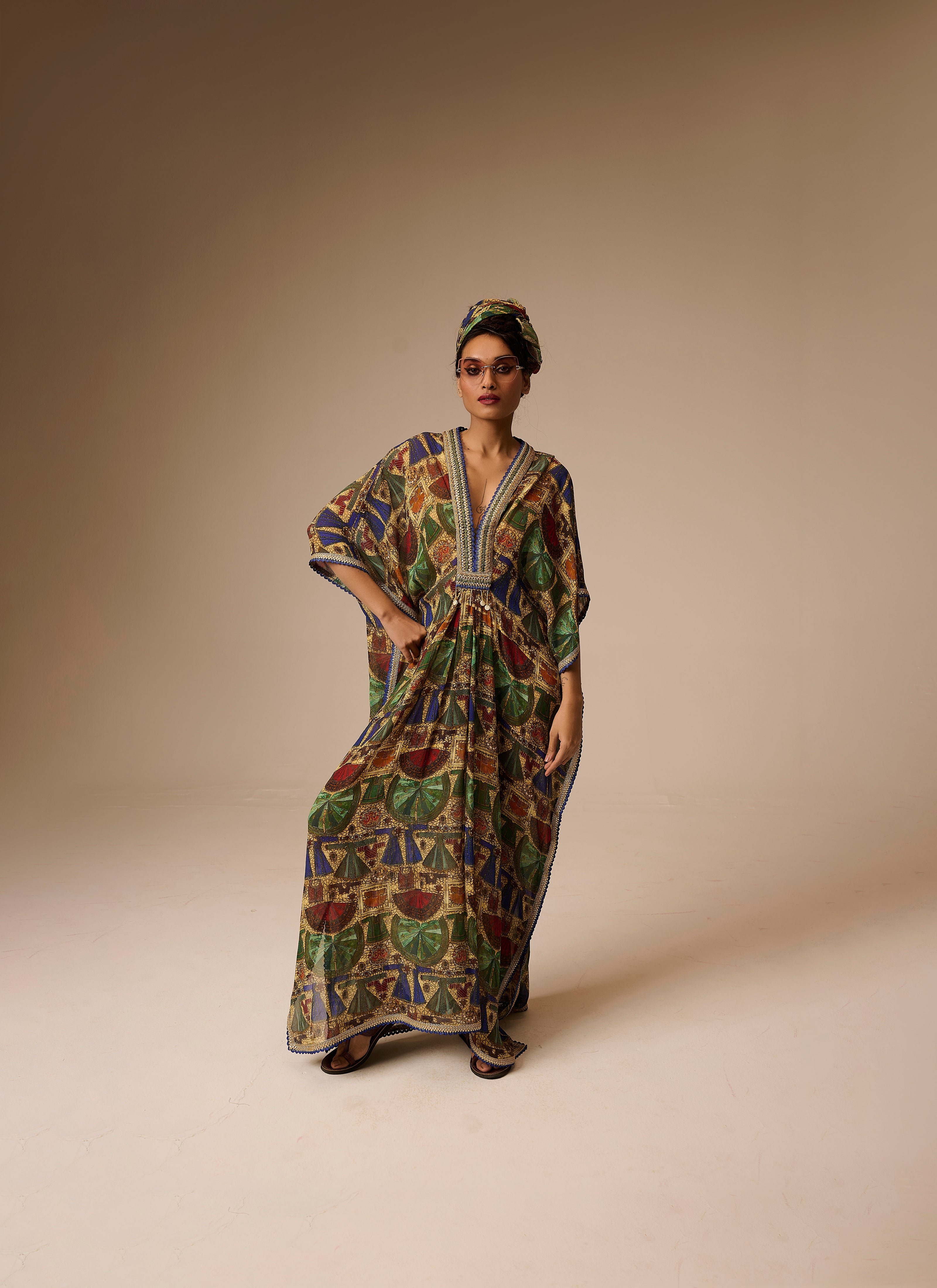 Woman wearing a colorful patterned dress and headscarf on a beige background