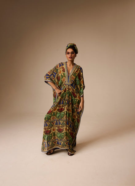 Woman wearing a colorful patterned dress and headscarf on a beige background