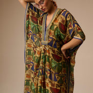 Woman wearing a colorful patterned dress and headscarf against a neutral background
