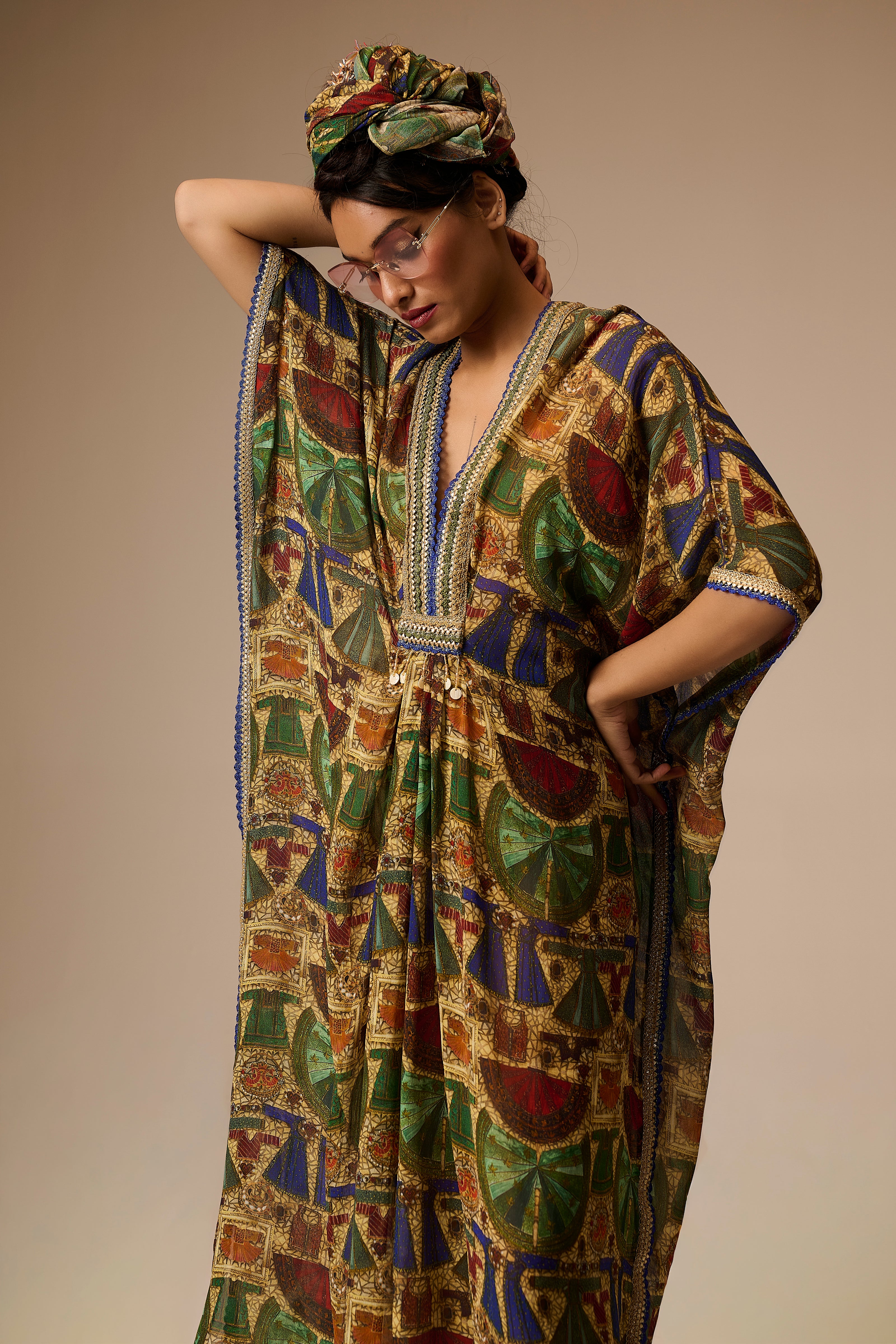 Woman wearing a colorful patterned dress and headscarf against a neutral background