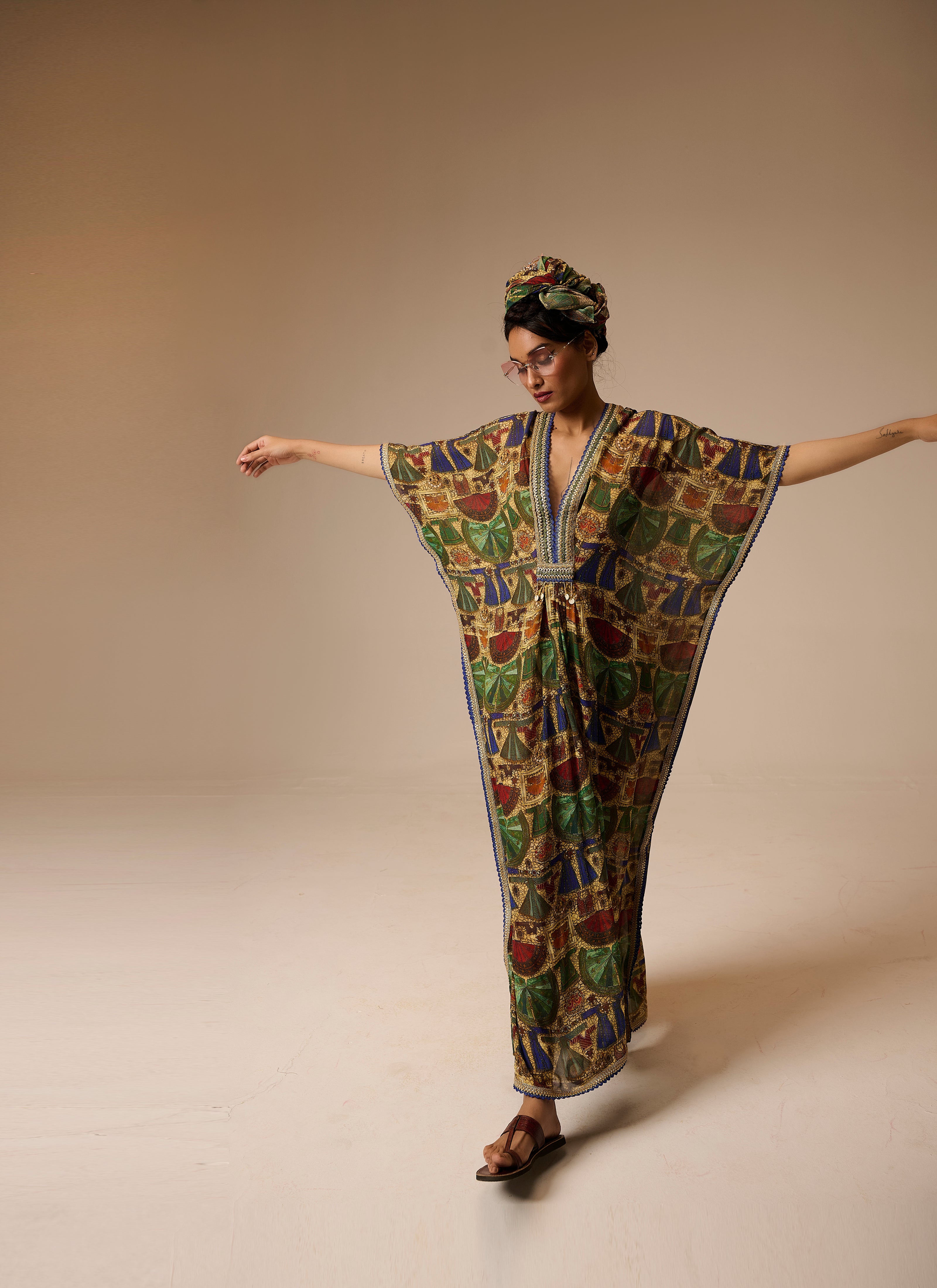 Woman wearing a colorful patterned dress and headscarf on a beige background