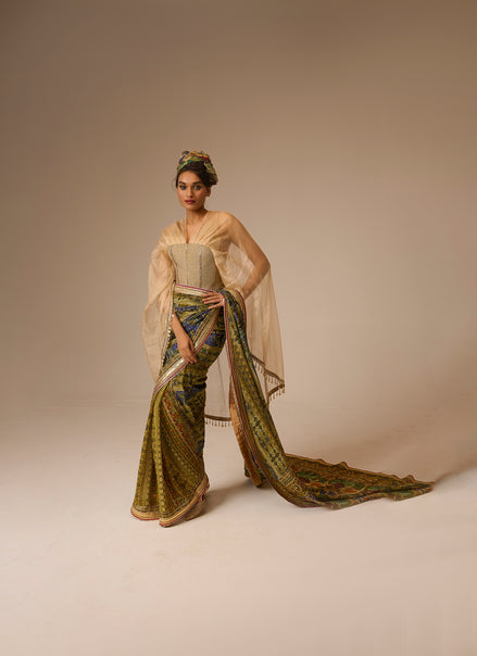 Woman in a traditional outfit with a long, flowing garment on a plain background