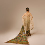 Woman wearing a traditional outfit with a long, colorful scarf on a plain background