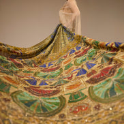 Woman with a colorful, patterned fabric draped over her shoulders against a neutral background
