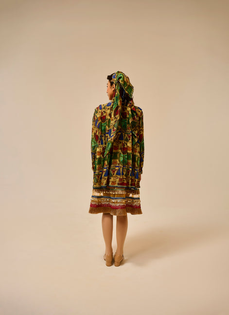 Person wearing a colorful patterned dress and headscarf on a beige background