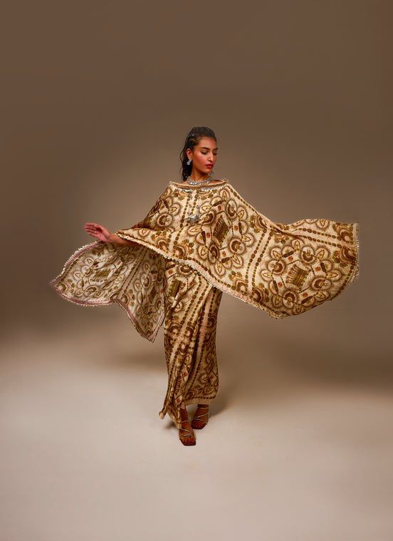 Woman wearing a gold and brown embroidered traditional outfit against a plain background