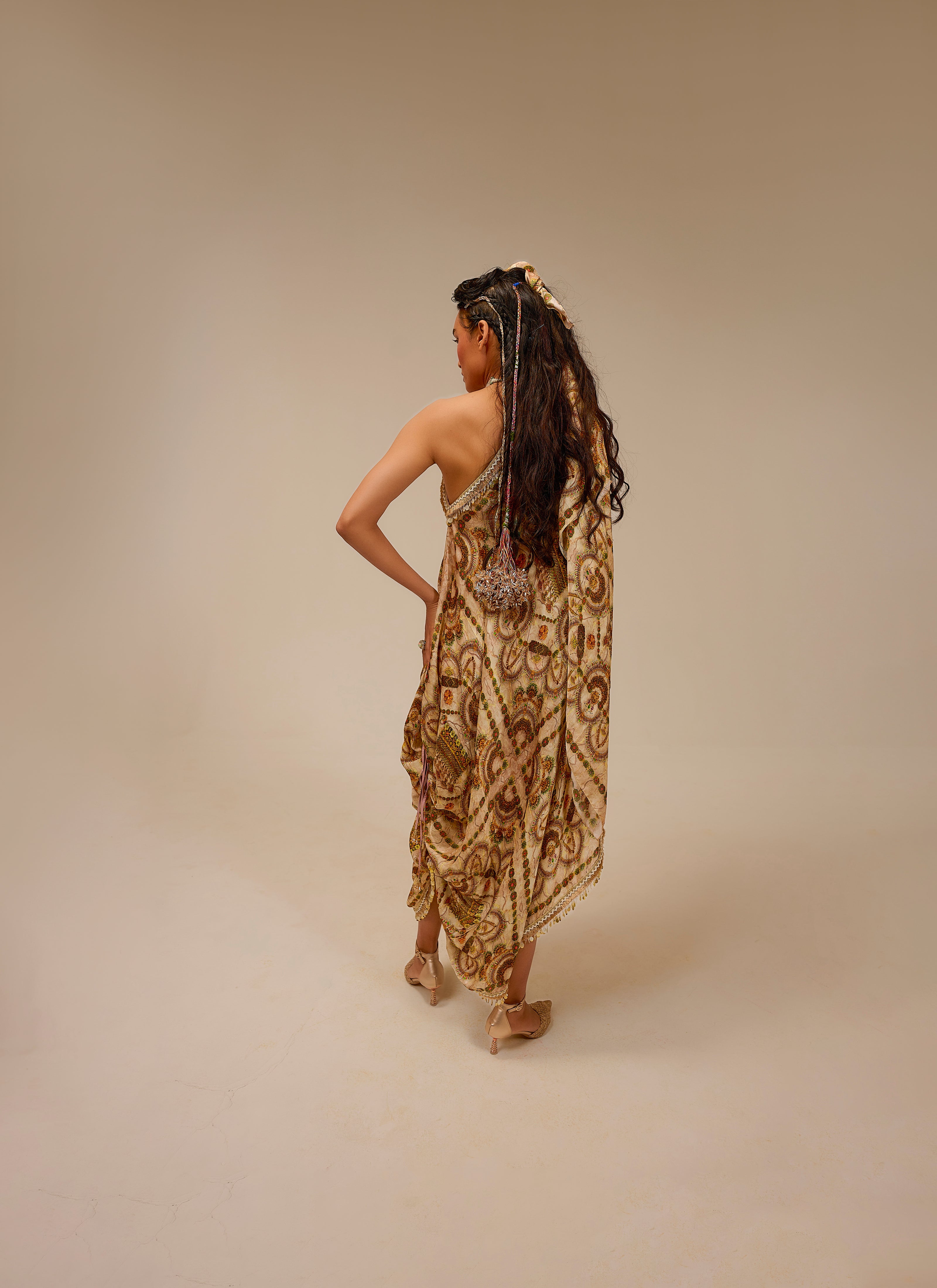 Woman in a patterned dress standing against a beige background