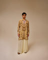 Man wearing a patterned kurta with white pants on a beige background