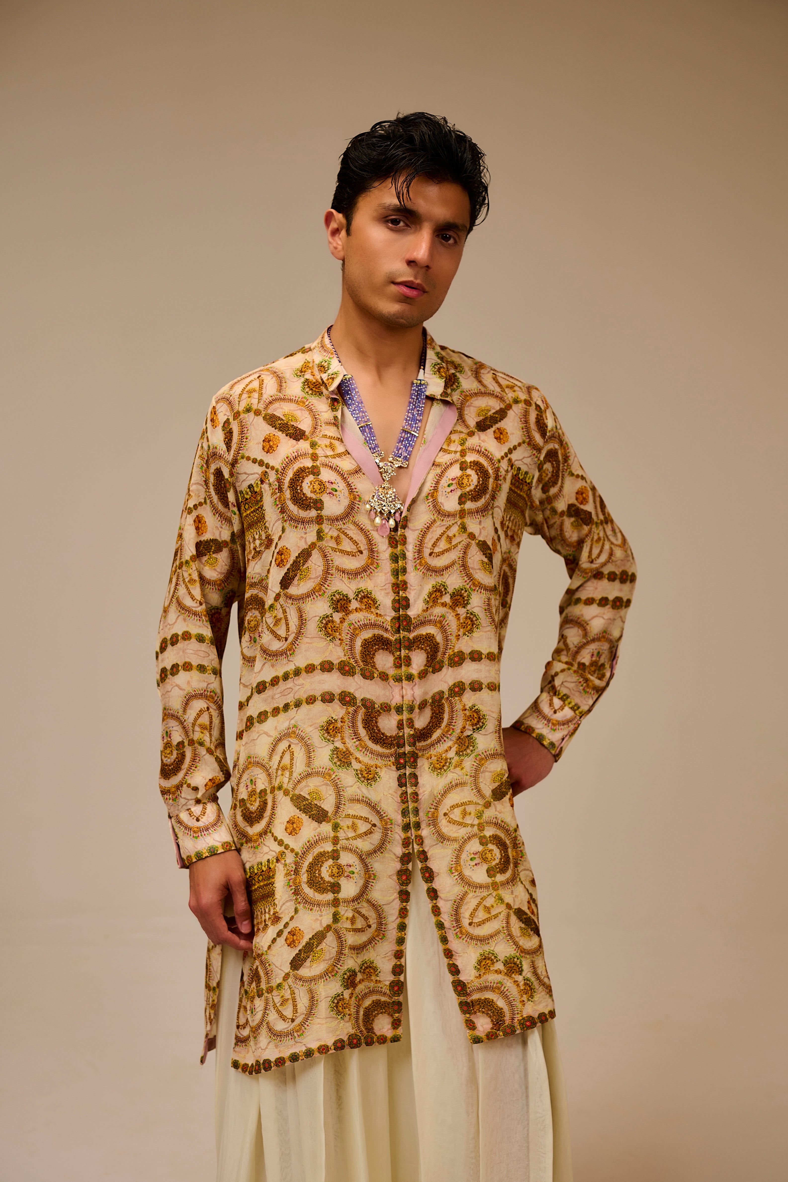 Man wearing a traditional embroidered kurta with a beige background