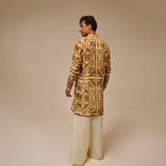 Man wearing a patterned jacket and white pants on a beige background