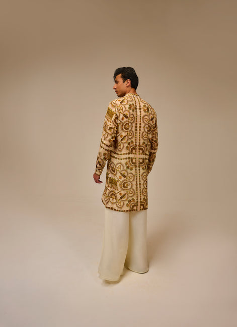 Man wearing a patterned jacket and white pants on a beige background