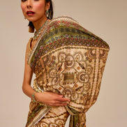 Woman wearing a traditional embroidered saree against a beige background