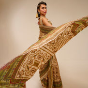 Woman in traditional attire with a flowing patterned fabric against a plain background