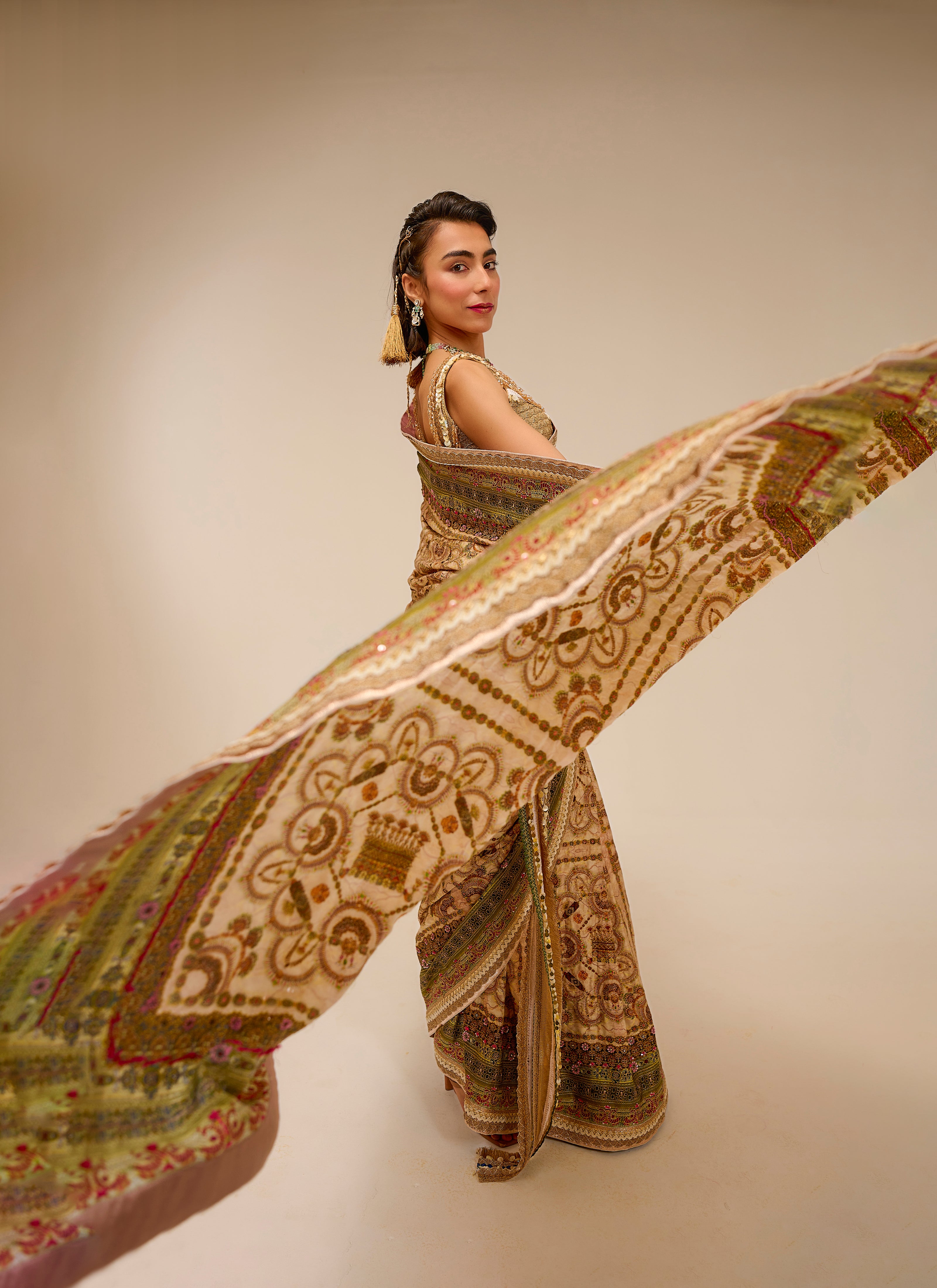 Woman in traditional attire with a flowing patterned fabric against a plain background
